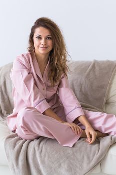 Young attractive woman dressed in beautiful colorful pajama posing as a model in her living room. Comfortable sleepwear, home relaxation and female fashion concept