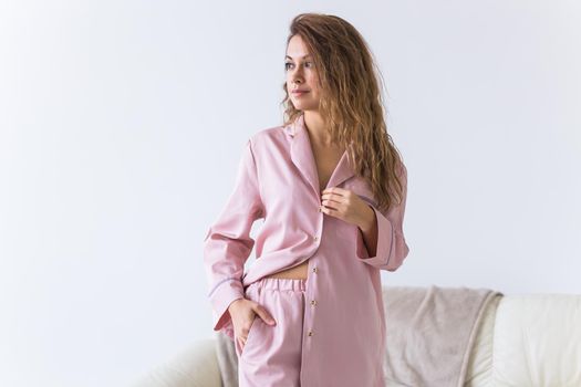 Young attractive woman dressed in beautiful colorful pajama posing as a model in her living room. Comfortable sleepwear, home relaxation and female fashion concept
