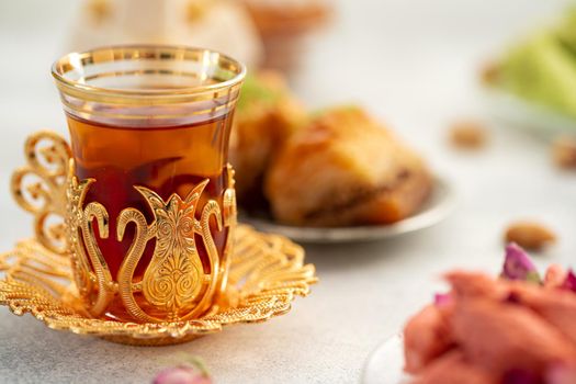 Assortment of Turkish delights with glass of tea on gray background, close up