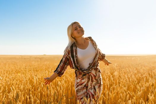 A girl in the midst of wheat spikelets. Caucasian woman posing with spikelets outside.
