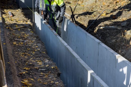 Construction road workers installing precast u-shape concrete drain at the reconstruction road
