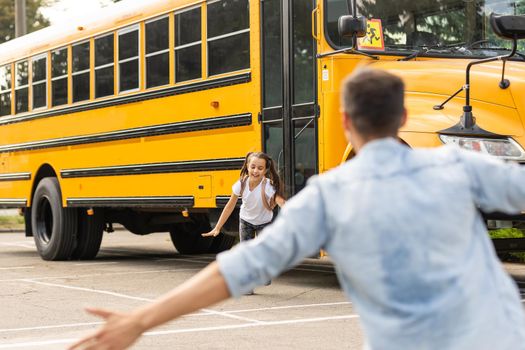 Father meeting little daughter coming out of school bus