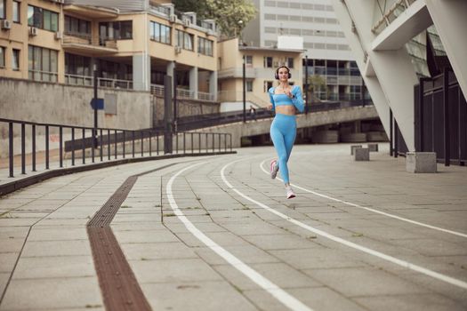 Young fit lady is doing fitness and jogging at urban place