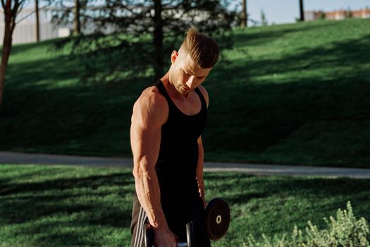 pumped up sports Vykhino in the park with dumbbell workout. High quality photo