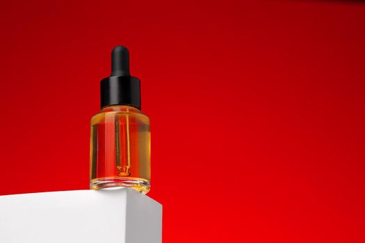 Beauty oil bottle with pipette against red background close up