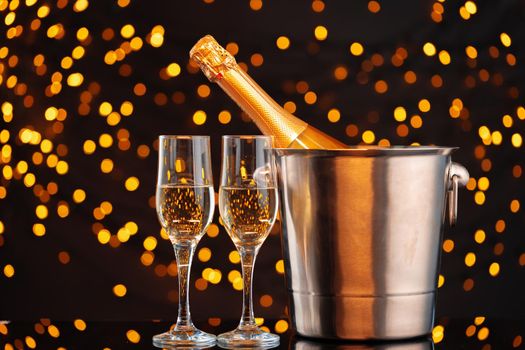 Champagne bottle and glasses on blurred lights background front view