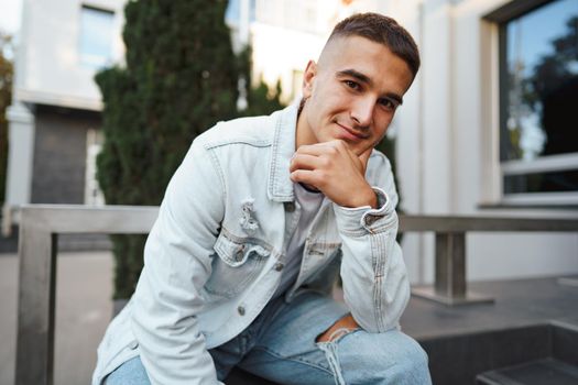 Young casual man sitting on stairs alone on city street