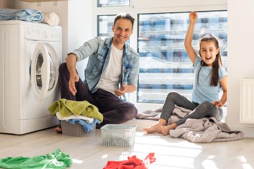 Happy family man father householder and child daughter in laundry with washing machine