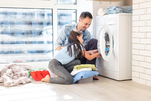 Happy family man father householder and child daughter in laundry with washing machine