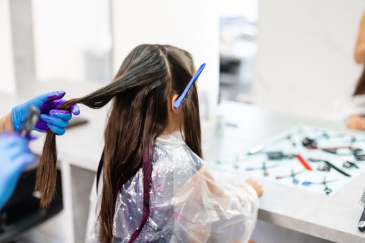 little girl dyes her hair purple in a hairdressing salon