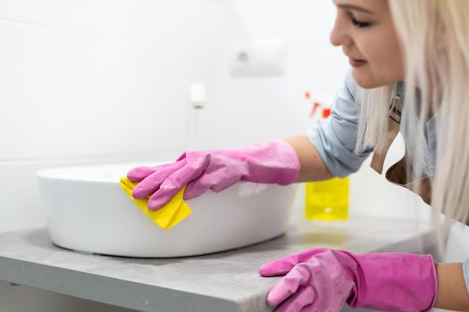 Cleaning - cleaning bathroom sink with spray detergent - housework, spring cleaning concept