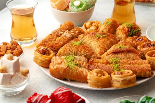 Various Turkish sweets and cup of tea on white textured background, close up