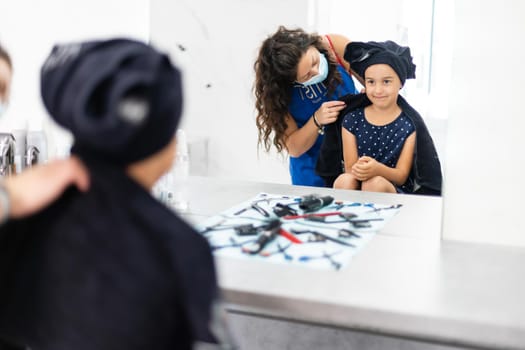 Pretty young girl's hair being arranged at the hair stylist