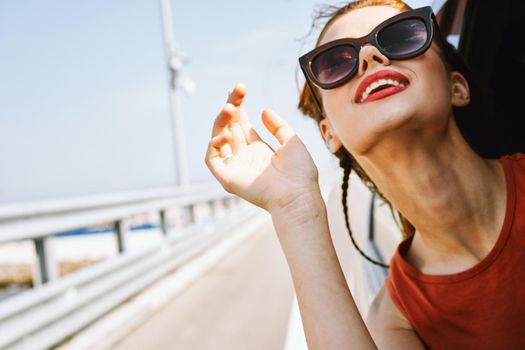 cheerful woman peeking out of the car window trip adventure lifestyle. High quality photo