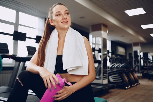 Young sporty woman having a drink in a gym after workout, close up