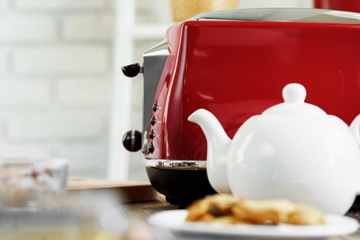 Ceramic teapot and toaster, kitchen table counter close up