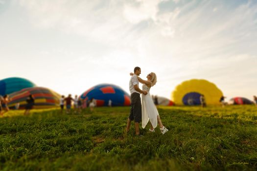 Beautiful romantic couple hugging at meadow. hot air balloon on a background