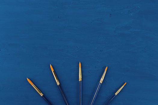 Blue paint brushes on classic blue background, view from above. High quality photo