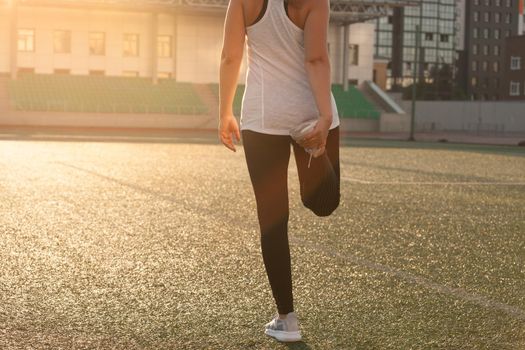 Sports girl doing stretching on the stadium lawn. High quality photo