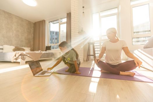 Young adult mother with her daughter watching online training together at home, looking a laptop