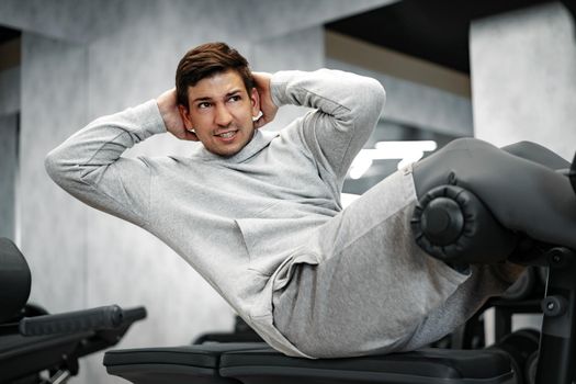 Young athlete doing abs exercises workout in modern gym, close up