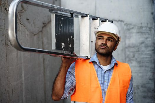 Professional builder carrying metal ladder, close up photo