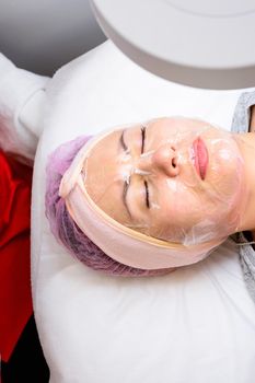 Transparent mask-film on the face of a woman, a visit to a beautician, facial care. new