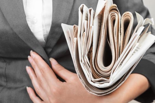 A woman holds stack of newspapers