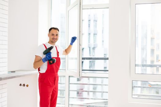 master with a screwdriver sets fittings on the window