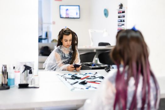 little girl dyes her hair purple in a hairdressing salon