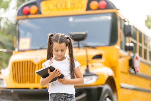 Girl with backpack near yellow school bus. Transport for students