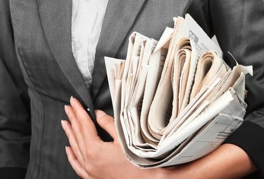 A woman in a jacket holds a stack of newspapers