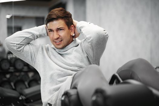 Young athlete doing abs exercises workout in modern gym, close up