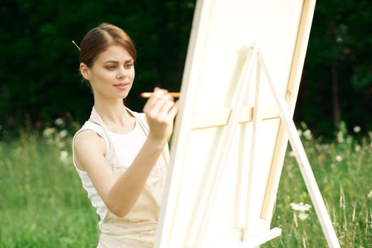 woman artist paints a picture near easel outdoors landscape creative. High quality photo