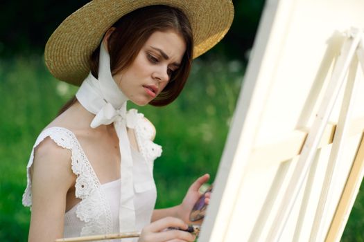 woman artist in hat with brush paints a picture. High quality photo