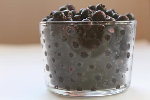 eating blueberry or currant berries in a glass glass on a white light background with a place to text the view from the side.