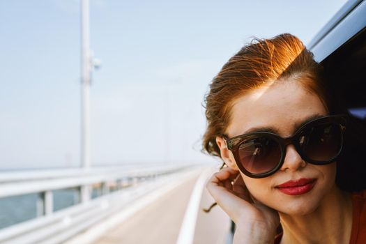 cheerful woman peeking out of the car window trip adventure lifestyle. High quality photo