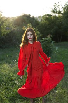 attractive woman in red dress outdoors in freedom field. High quality photo