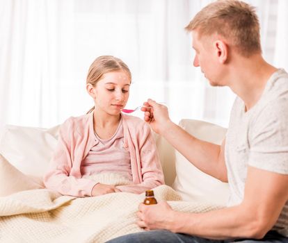 Careful parent giving mixture to chickenpox ill tired daughter