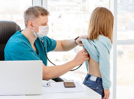 Doctor listening little girl by phonendoscope in clinic