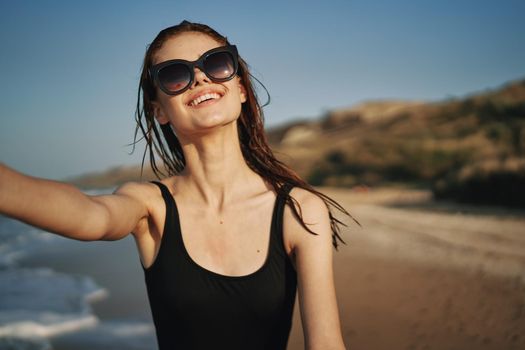cheerful woman in a black swimsuit walking along the beach tropics summer. High quality photo