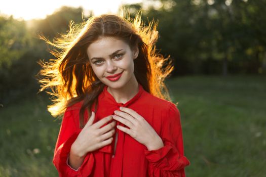 cheerful woman in a red dress in a field outdoors fresh air. High quality photo