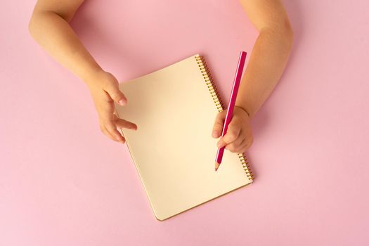 Kid's hands writing in open notebook, top view, copy space. To do list, letter to Santa