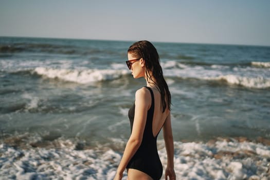 woman in black swimsuit walking on the beach ocean summer. High quality photo