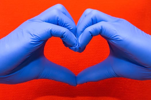 Blue latex gloves for medical protection in heart form symbol, support the doctors and nurses, Covid-19, coronavirus. red background