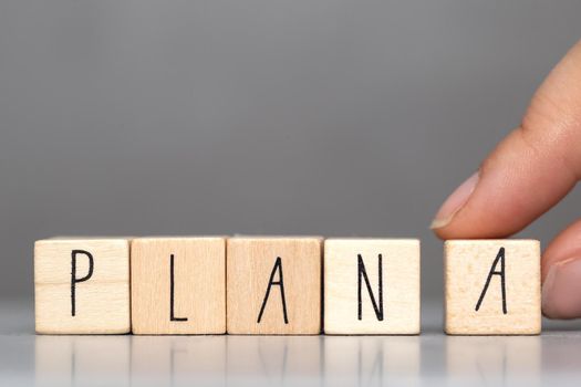Wooden cube with PLAN A text on grey background. Goals, success, strategy, solution and business concepts close-up