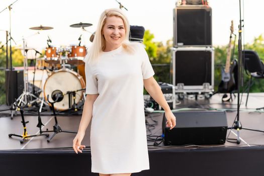 attractive woman dressed in white dress in summer open air theater on chair alone, spring street style fashion trend, social distancing