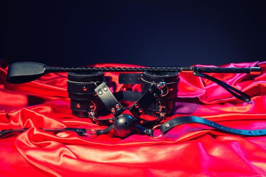 Adult sex games. Kinky lifestyle. Spank, Bondage and gag ball on the red linen. Bdsm outfit Concept - Image