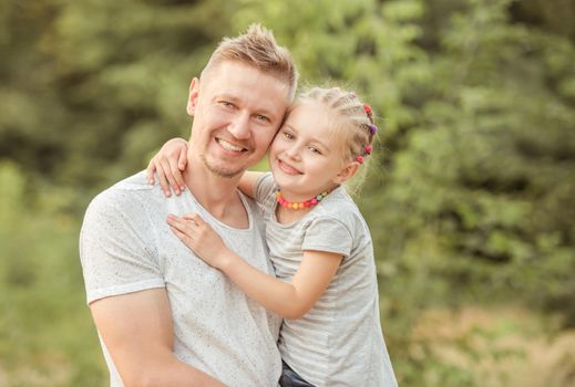 Happy dad holding smiling little daughter hugging