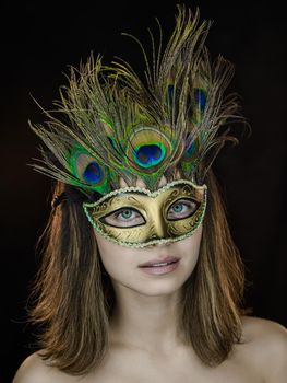 Close-up portrait of a beautiful green-eyed woman in a Venetian carnival mask on a dark background. ring flash